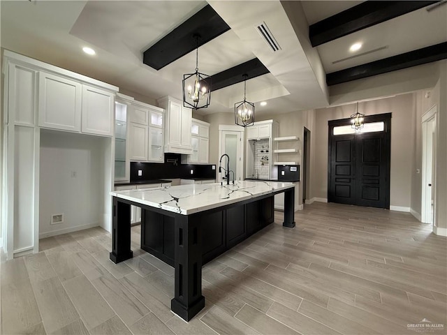 kitchen featuring white cabinetry, decorative light fixtures, a kitchen bar, and a spacious island