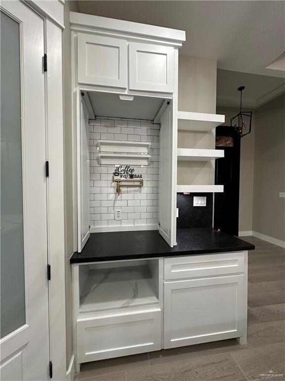 kitchen with white cabinetry, dark hardwood / wood-style floors, decorative light fixtures, and backsplash