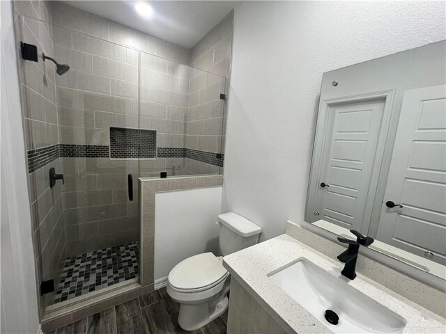 bathroom featuring hardwood / wood-style floors, toilet, an enclosed shower, and vanity