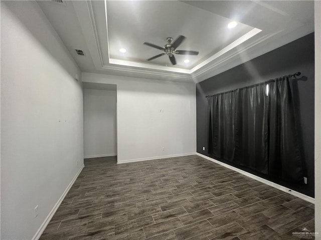 empty room featuring dark hardwood / wood-style floors, ceiling fan, and a tray ceiling