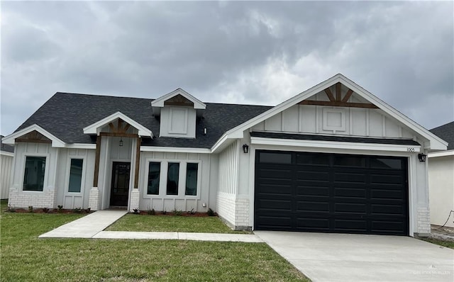 view of front of home with a front yard, an attached garage, brick siding, and board and batten siding