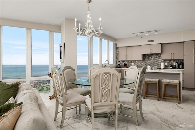 dining room featuring a notable chandelier, marble finish floor, and a water view