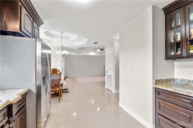 kitchen with light tile patterned floors, stainless steel fridge, baseboards, and dark brown cabinets