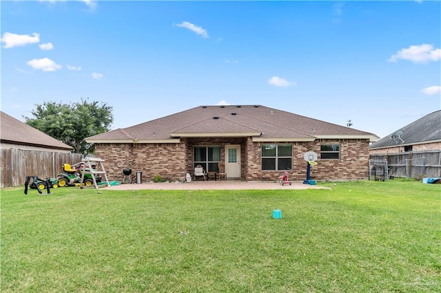 rear view of property featuring a yard, brick siding, a patio, roof with shingles, and a fenced backyard