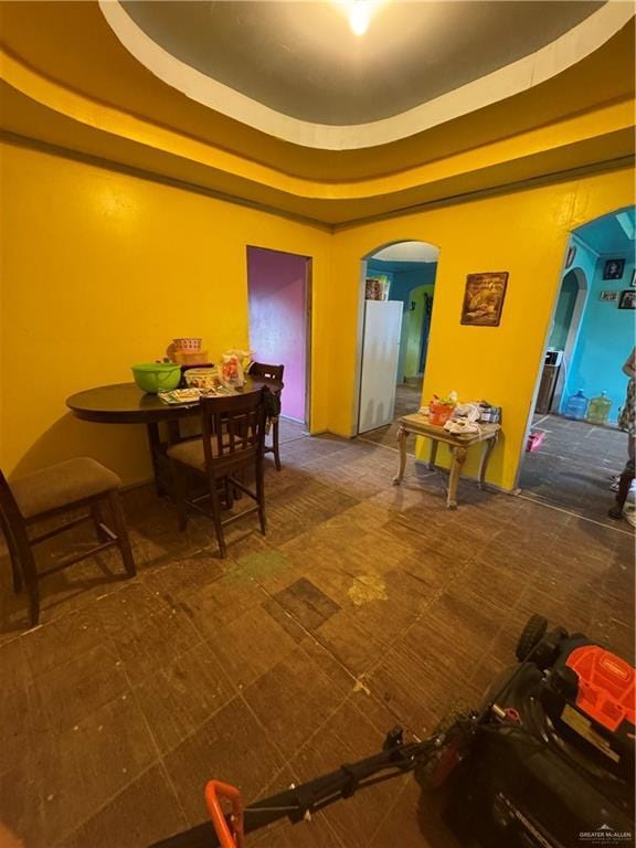 dining area featuring a tray ceiling and arched walkways