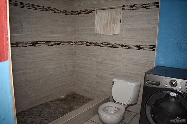 bathroom featuring toilet, washer / dryer, and a tile shower