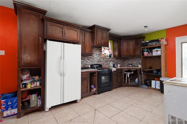 kitchen with backsplash, light tile patterned floors, dark brown cabinets, white fridge, and black range with gas cooktop