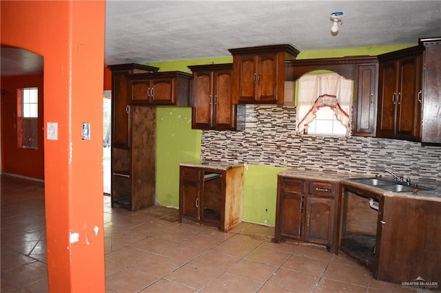 kitchen with dark brown cabinetry, sink, light tile patterned floors, and tasteful backsplash