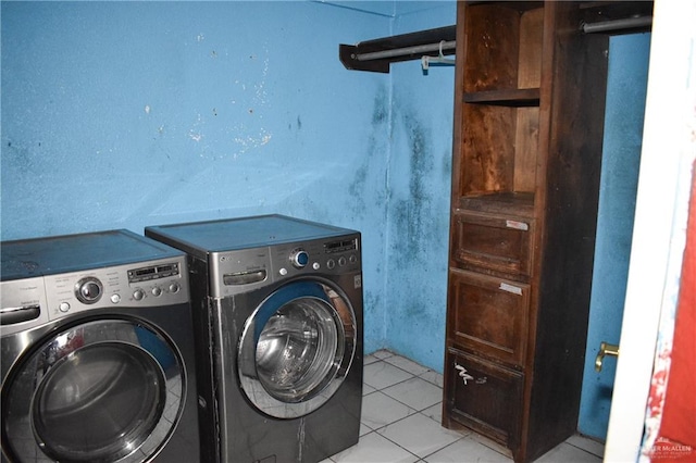 laundry area with independent washer and dryer and light tile patterned floors