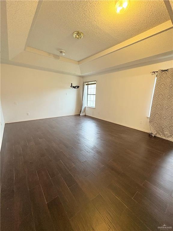 2218 Lawndale Rd, Mission, TX 78572 - empty room featuring baseboards, wood finished floors, a tray ceiling, and a textured ceiling