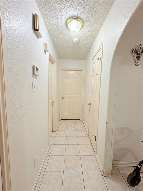 2218 Lawndale Rd, Mission, TX 78572 - hall with light tile patterned flooring, a textured ceiling, and baseboards