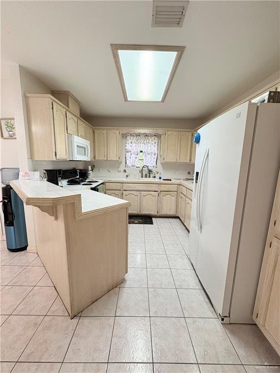2218 Lawndale Rd, Mission, TX 78572 - kitchen featuring visible vents, light tile patterned floors, a sink, white appliances, and a peninsula