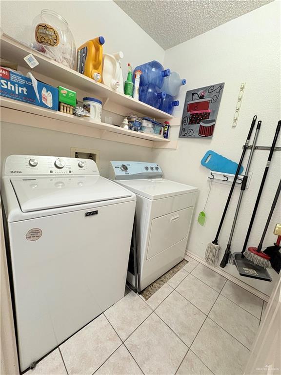 2218 Lawndale Rd, Mission, TX 78572 - laundry area with light tile patterned flooring, a textured ceiling, washer and dryer, and laundry area