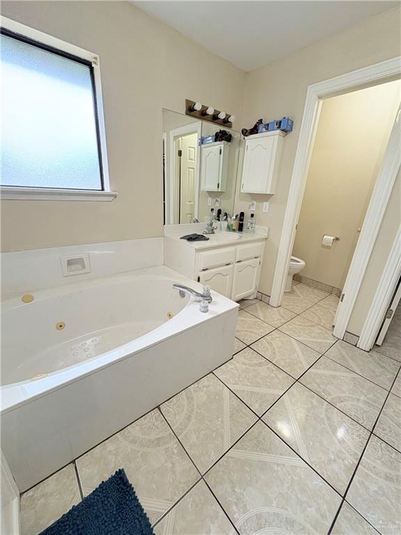 2218 Lawndale Rd, Mission, TX 78572 - bathroom featuring a jetted tub, tile patterned flooring, vanity, and toilet