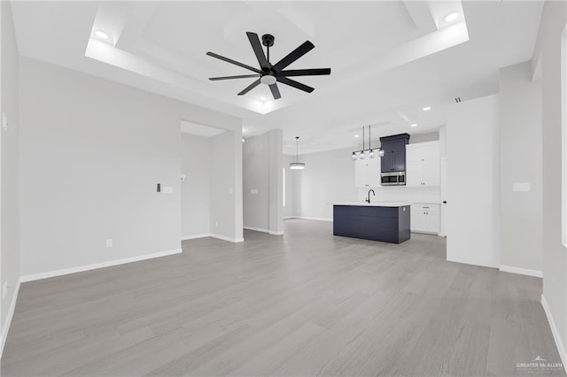 910 Azalea St, Mission, TX 78574 - unfurnished living room with a raised ceiling, ceiling fan, light wood finished floors, and recessed lighting