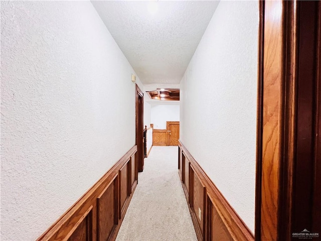 corridor featuring light colored carpet and a textured ceiling