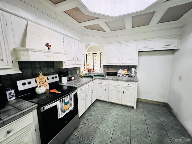 kitchen with white cabinetry, premium range hood, tile countertops, stainless steel electric range, and dark tile patterned flooring