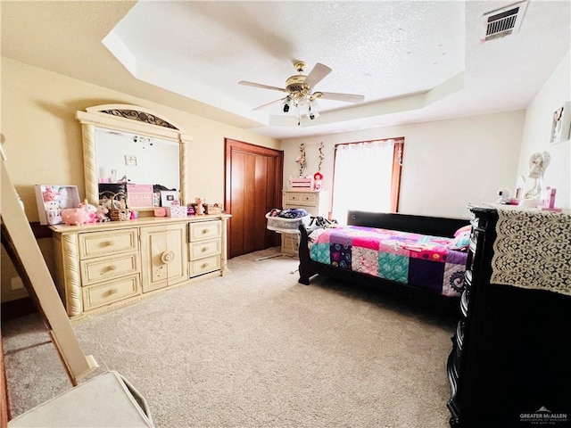 carpeted bedroom featuring ceiling fan, a textured ceiling, and a tray ceiling