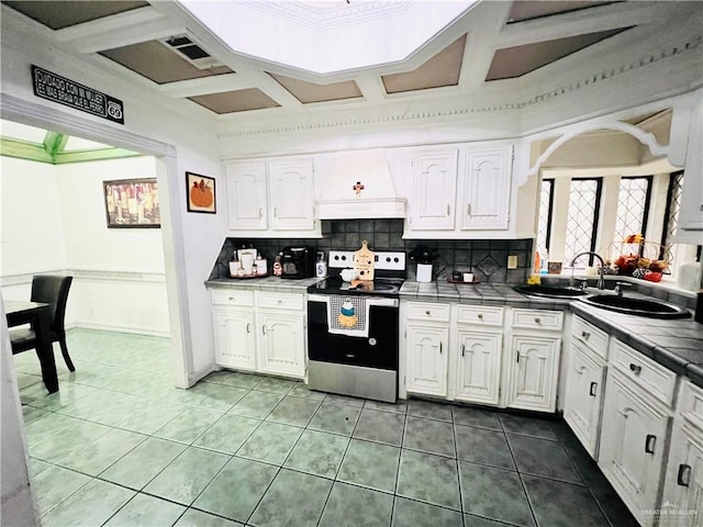 kitchen with tile countertops, white cabinetry, and electric stove