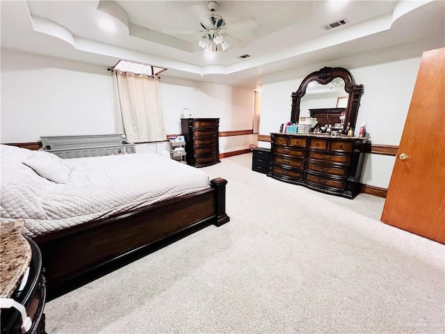 carpeted bedroom with ceiling fan and a tray ceiling