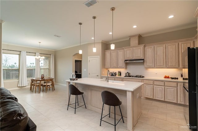 kitchen featuring visible vents, arched walkways, freestanding refrigerator, under cabinet range hood, and a sink