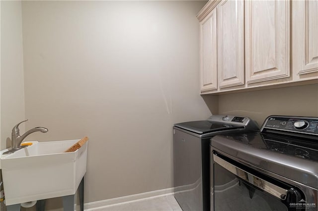 washroom featuring cabinet space, baseboards, separate washer and dryer, and a sink