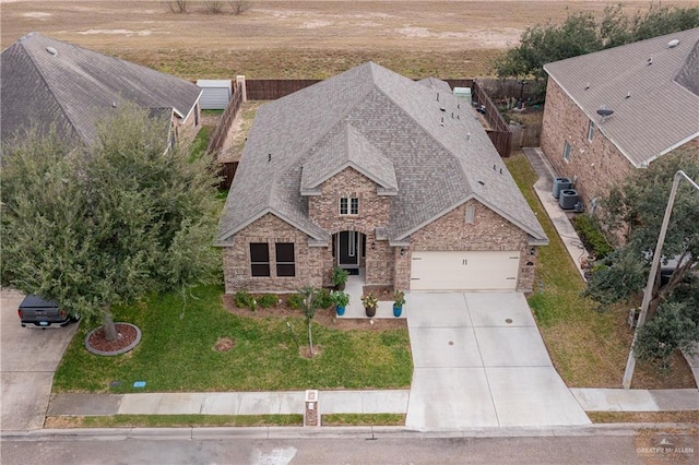 view of front of home featuring roof with shingles, brick siding, concrete driveway, an attached garage, and a front yard