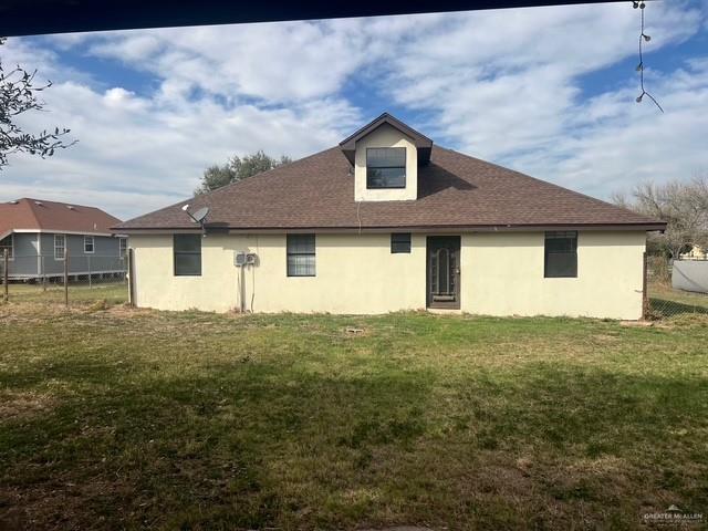 back of property featuring fence, a lawn, and stucco siding