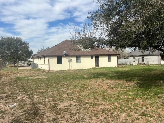 back of house featuring a lawn and fence