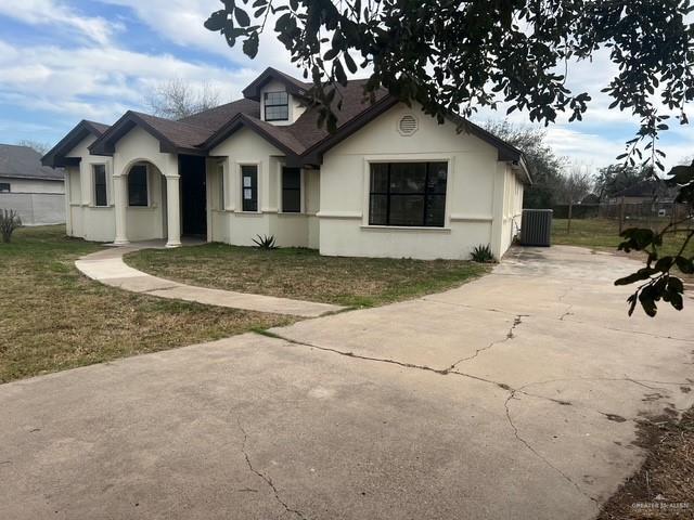 view of front facade featuring concrete driveway, a front lawn, fence, and stucco siding