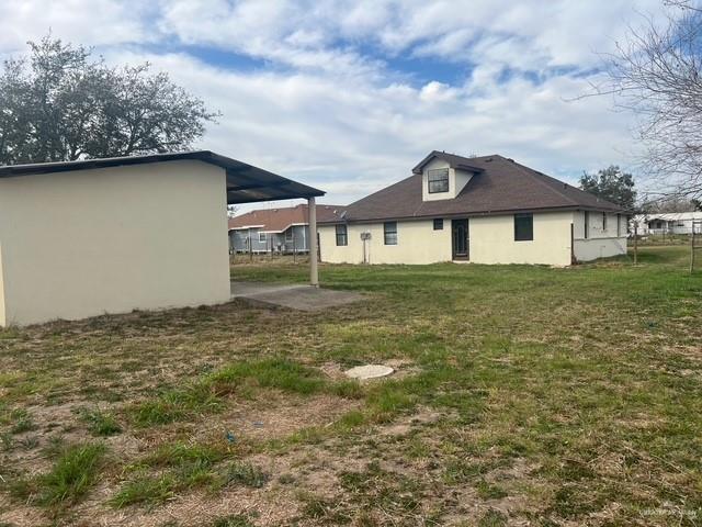 rear view of property featuring a yard and stucco siding