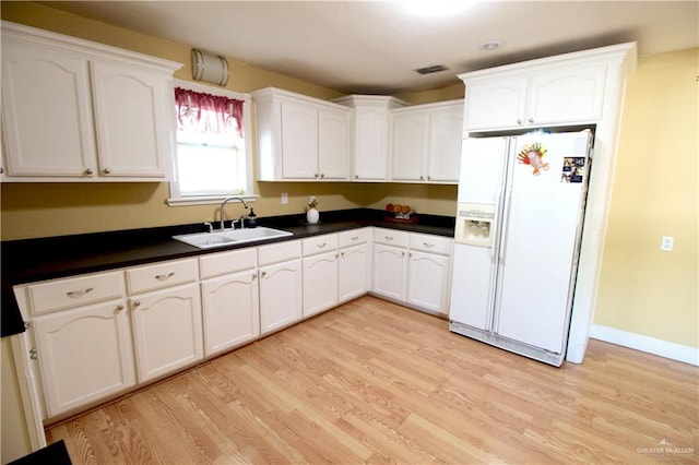 kitchen featuring white fridge with ice dispenser, white cabinets, light hardwood / wood-style floors, and sink