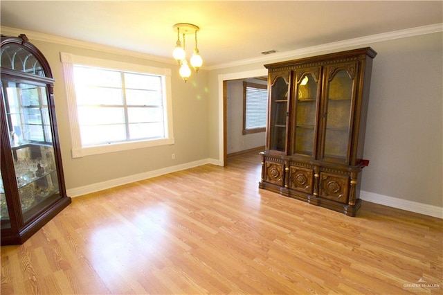 unfurnished dining area with light wood-type flooring and crown molding