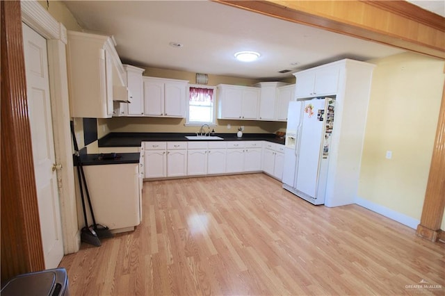 kitchen featuring light wood-type flooring, white cabinetry, white fridge with ice dispenser, and sink