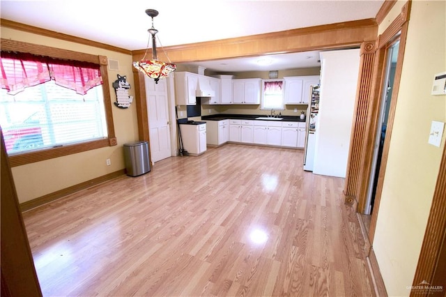 kitchen with crown molding, pendant lighting, white refrigerator, white cabinets, and light hardwood / wood-style floors