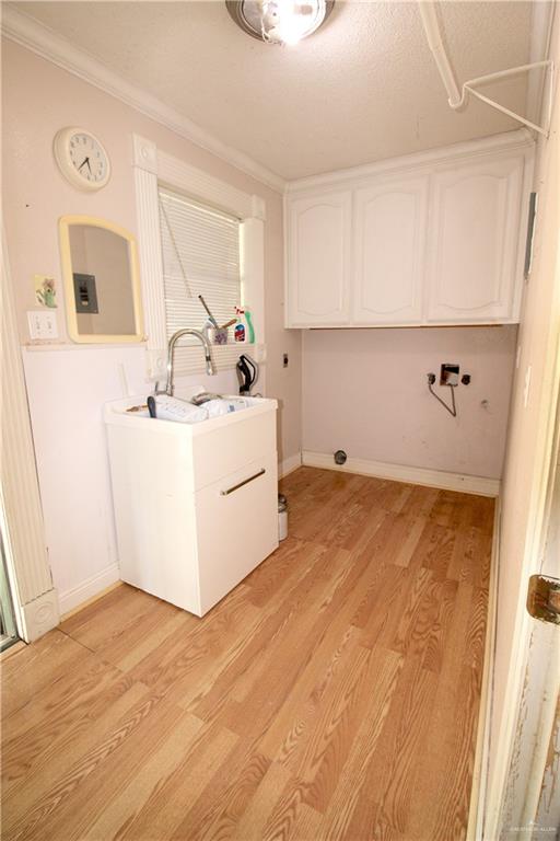 laundry area featuring cabinets, electric panel, crown molding, hookup for a washing machine, and light wood-type flooring