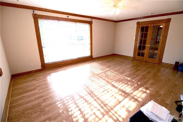 empty room featuring wood-type flooring, french doors, ornamental molding, and ceiling fan