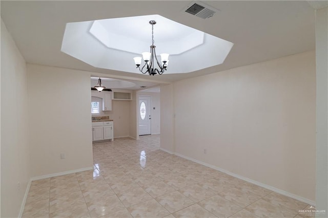 unfurnished room with baseboards, visible vents, a chandelier, and a tray ceiling