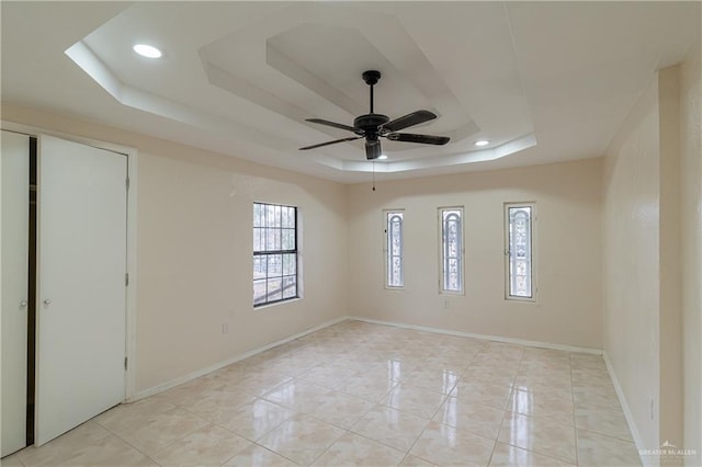 unfurnished bedroom featuring a tray ceiling, recessed lighting, baseboards, and light tile patterned floors