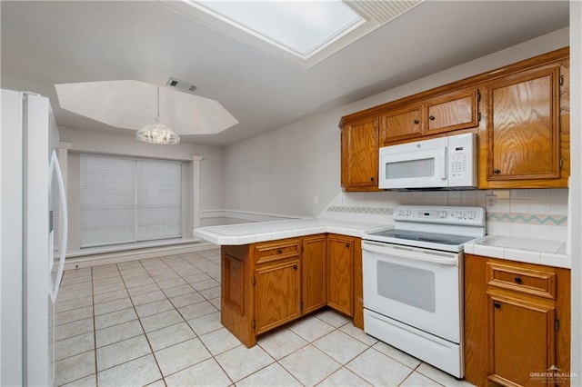 2106 Quail Ln, Mission, TX 78572 - kitchen featuring white appliances, a peninsula, brown cabinetry, and light tile patterned floors