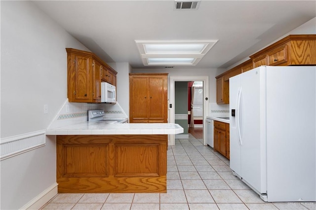 2106 Quail Ln, Mission, TX 78572 - kitchen with white appliances, a peninsula, brown cabinetry, and backsplash