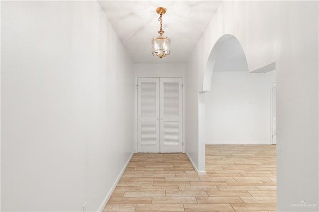 hallway with light hardwood / wood-style floors and a chandelier