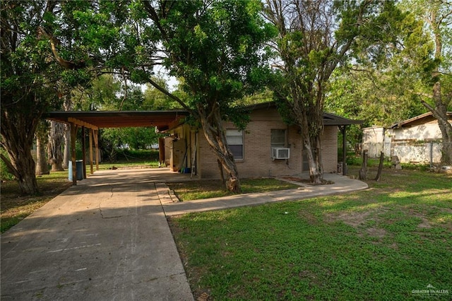 view of front of property featuring a front lawn, cooling unit, concrete driveway, a carport, and brick siding