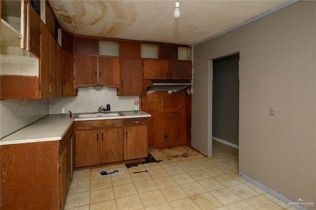 kitchen with light floors, brown cabinetry, light countertops, and tasteful backsplash