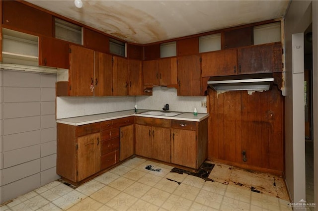 kitchen with light countertops, tasteful backsplash, brown cabinetry, and a sink