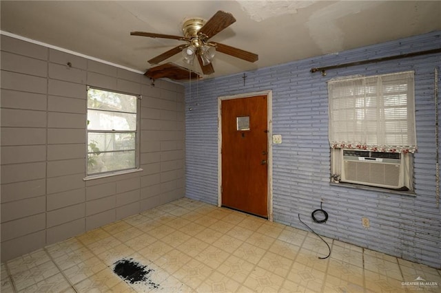 empty room with a ceiling fan, cooling unit, brick wall, and tile patterned floors