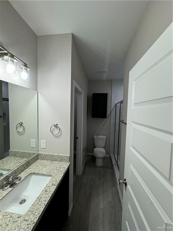 bathroom with walk in shower, vanity, wood-type flooring, and toilet