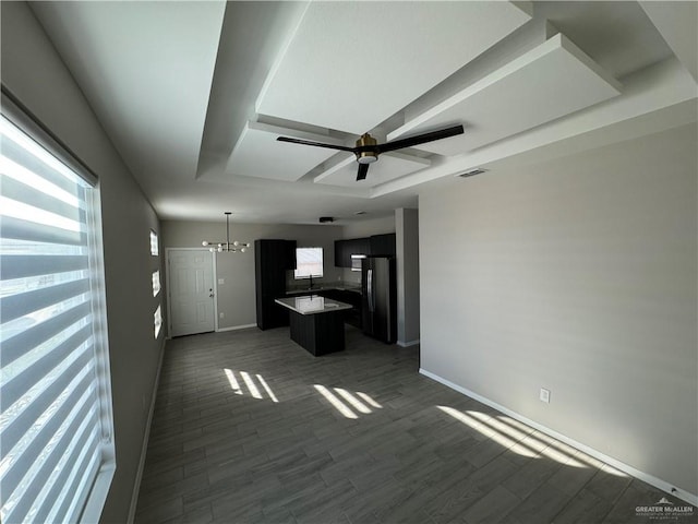 unfurnished living room with a wealth of natural light, dark wood-type flooring, and ceiling fan with notable chandelier