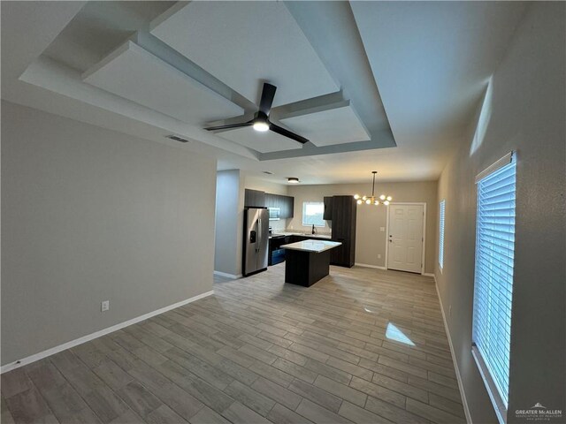 kitchen featuring a center island, a raised ceiling, stainless steel refrigerator with ice dispenser, decorative light fixtures, and light hardwood / wood-style floors