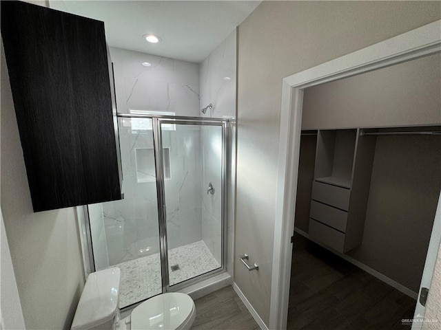 bathroom with wood-type flooring, a shower with shower door, and toilet